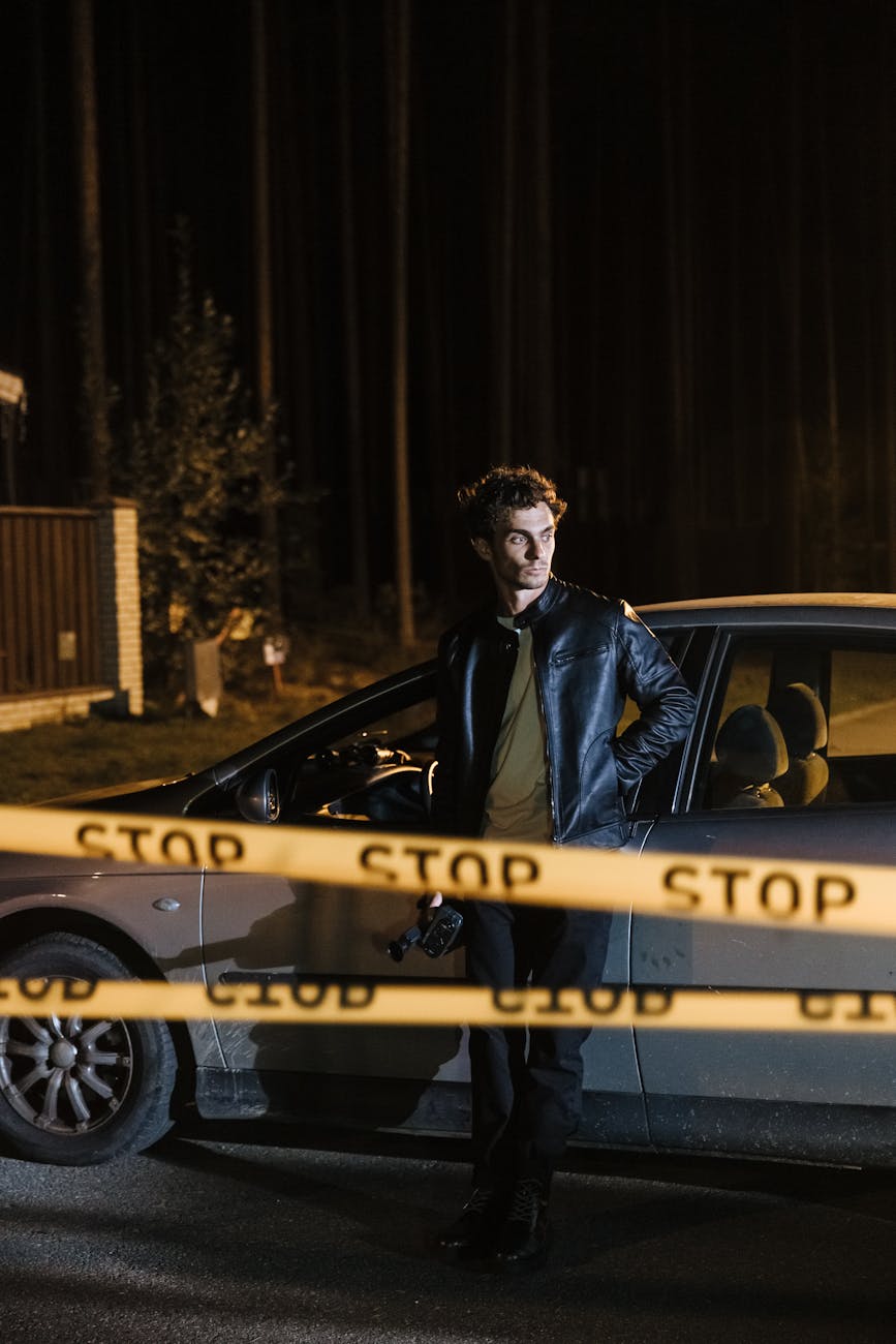 Guy leaning against his car inside a crime scene.